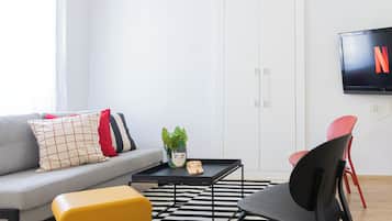 A modern living room with a sofa, a coffee table, a yellow chair, and a TV mounted on the wall.