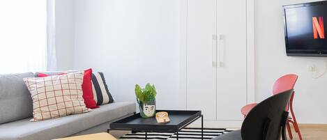 A modern living room with a sofa, a coffee table, a yellow chair, and a TV mounted on the wall.