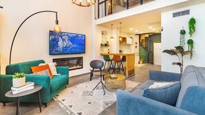 Un salon moderne avec un canapé vert, un canapé bleu, une cheminée et un téléviseur à écran plat.