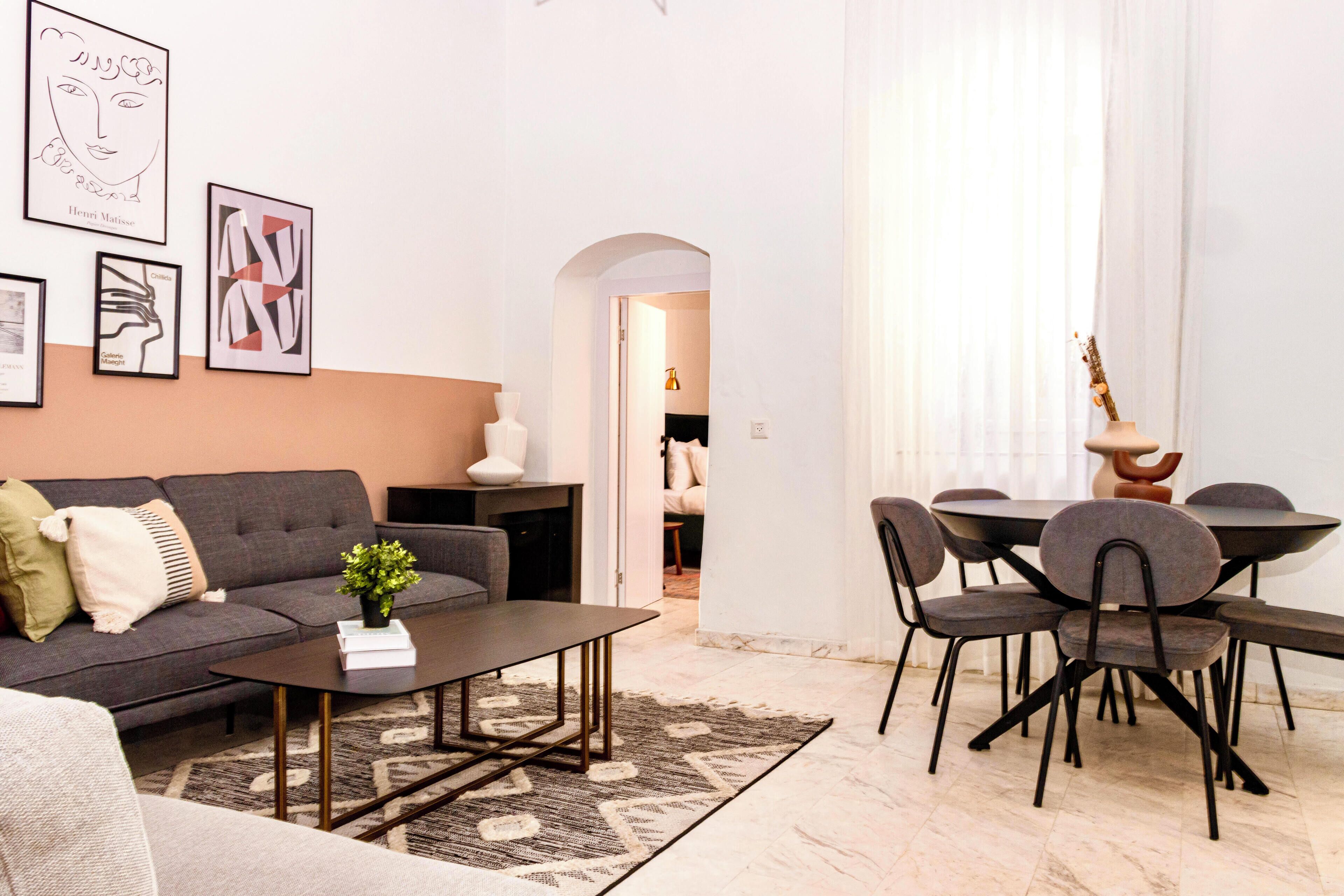 A modern living room with a grey sofa, a coffee table, and a dining area with a table and chairs.