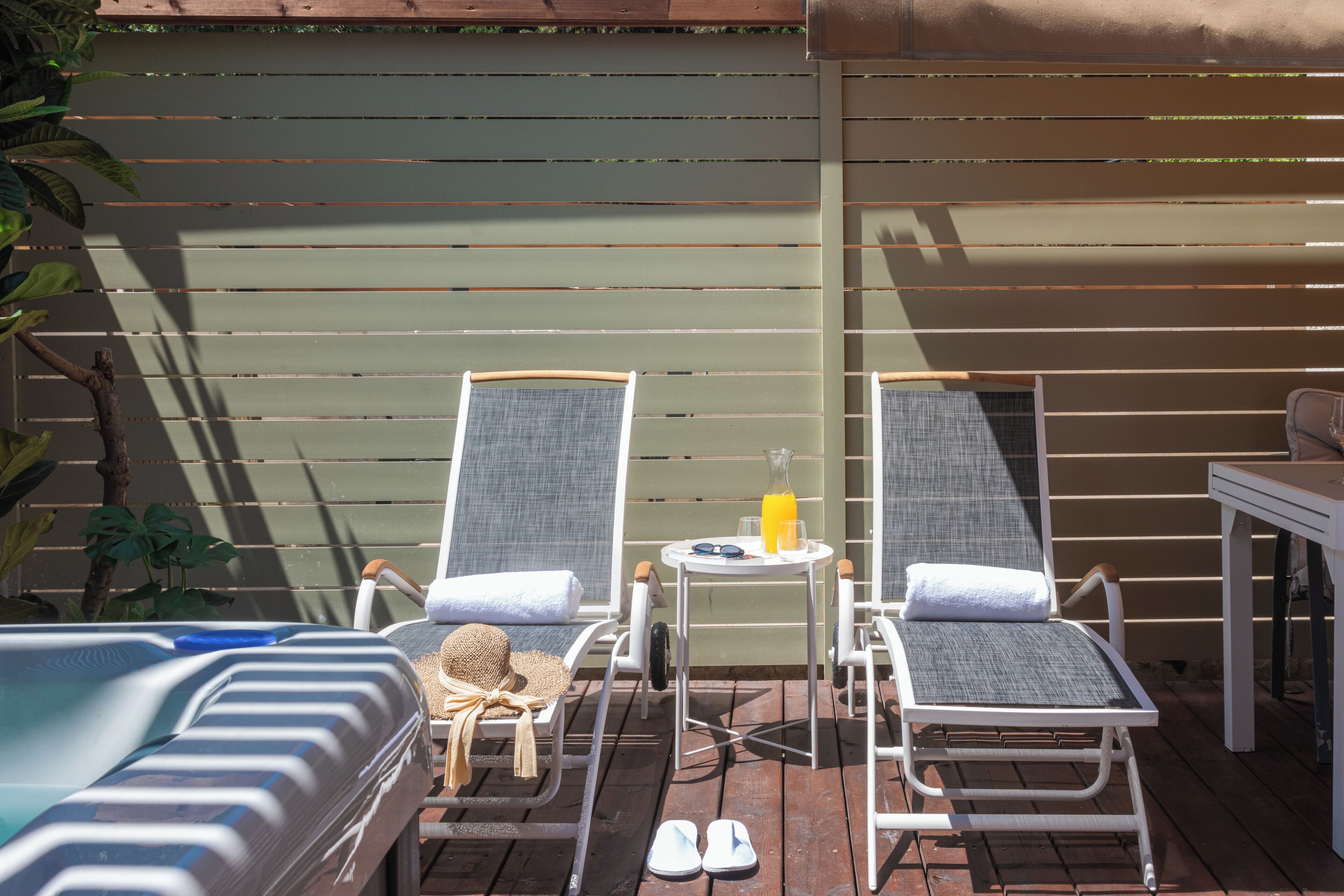 A poolside area with two lounge chairs, a small table with a drink, and a sun umbrella.