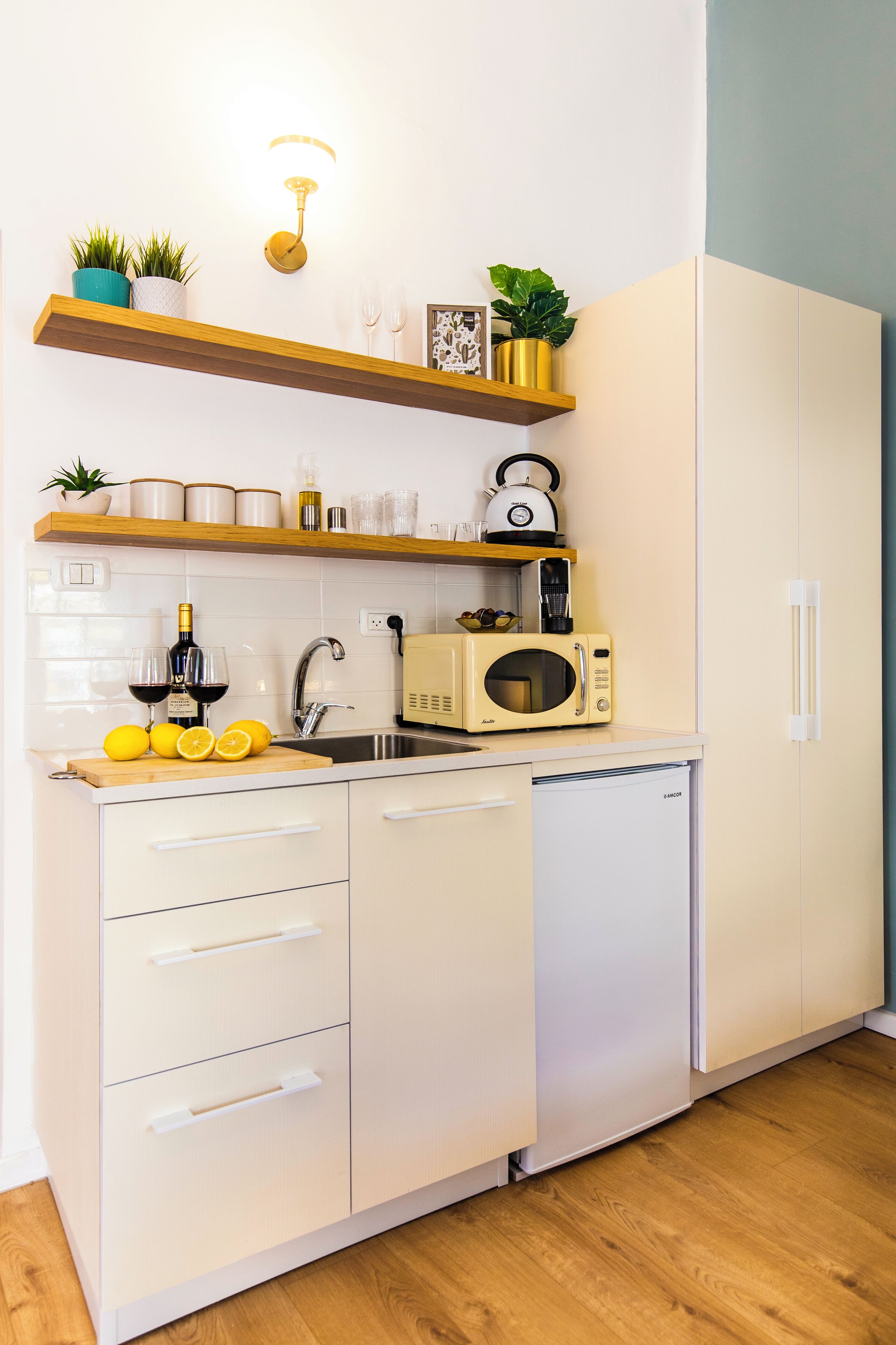 A compact kitchen with white cabinets, a wooden countertop, a microwave, and a sink.