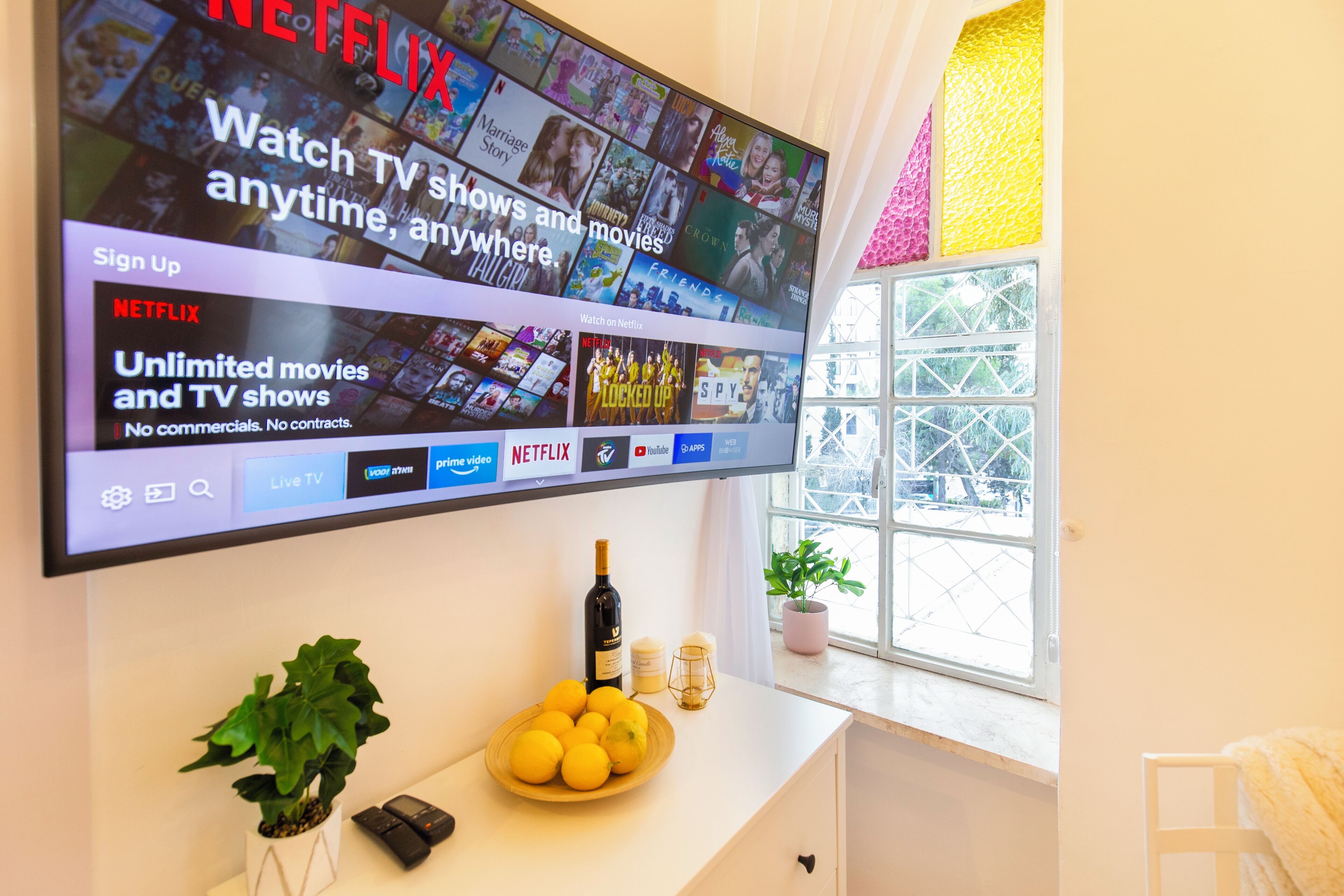 A flat-screen TV mounted on a wall displaying a Netflix interface with various shows and movies.