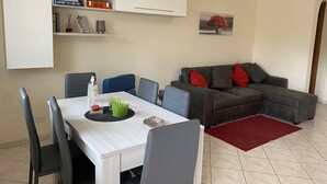 Un soggiorno moderno con un tavolo da pranzo, sedie, un divano e un tappeto rosso.