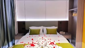 A hotel room with a bed, green and white bedding, a nightstand, and a wall-mounted shelf. - Green Tree Inn Zhixuan Hotel (Nanning)