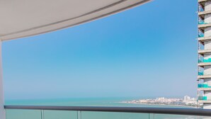 A balcony with wicker chairs overlooking a beach and cityscape. - Playa Cartagena (Cartagena)
