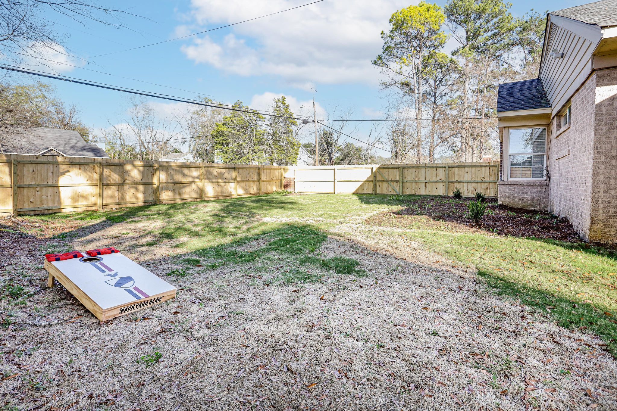 Patio con valla de madera, una casa y un juego al aire libre.