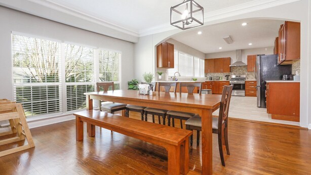 Una cocina amplia con armarios de madera, una mesa de comedor grande y una lámpara colgante.