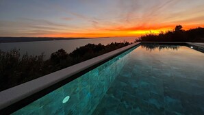 Una piscina infinita con vistas despejadas al atardecer sobre el agua.
