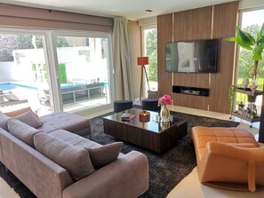 A modern living room with a large sofa, a coffee table, and a TV mounted on the wall. - Villa Corado with Pool (Umag)