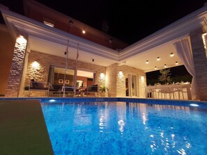 A swimming pool with a stone wall and a covered patio area. - Villa Corado with Pool (Umag)