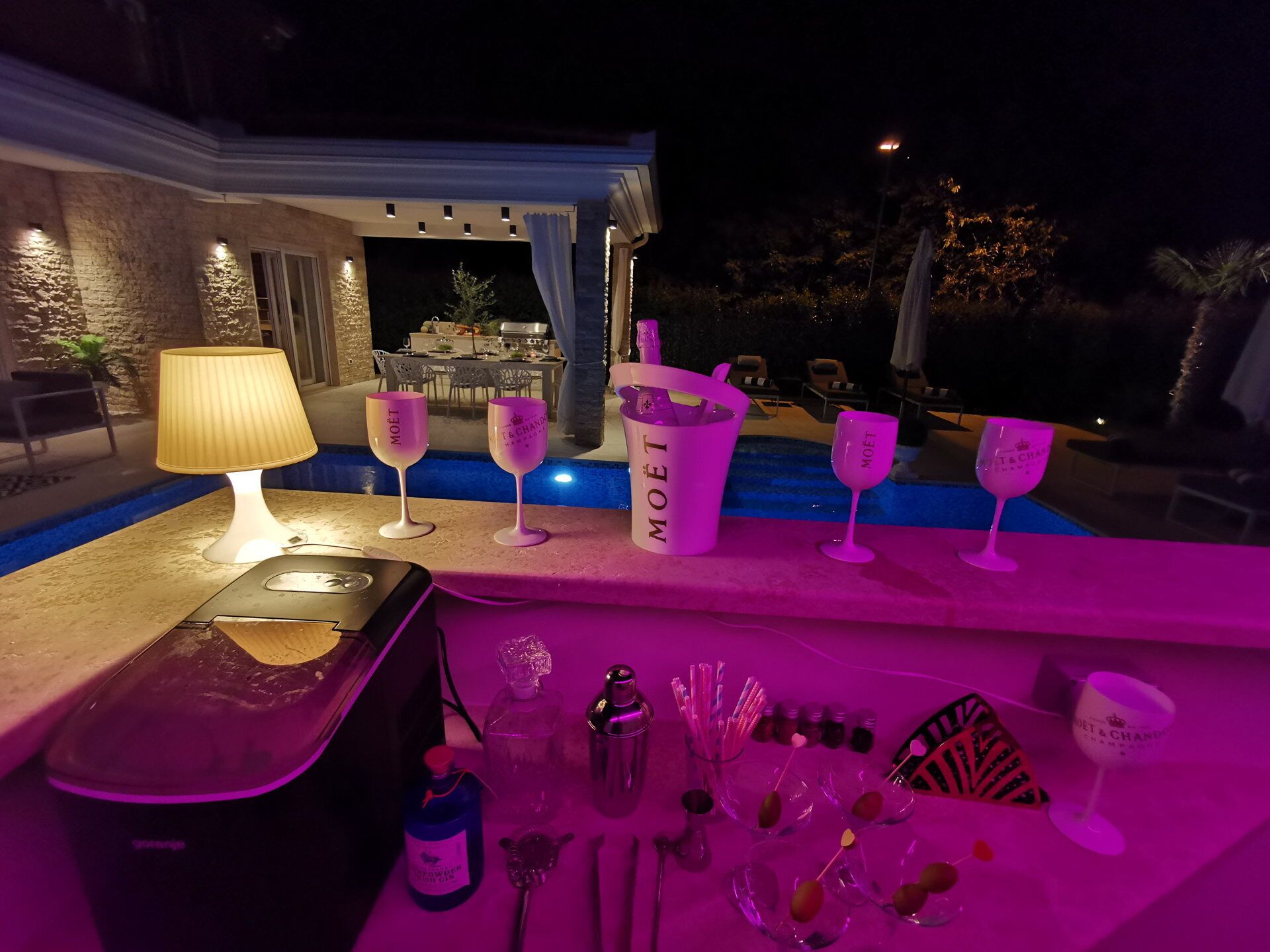 A bar area with a poolside setting, including a bar counter, a pool, and outdoor seating.