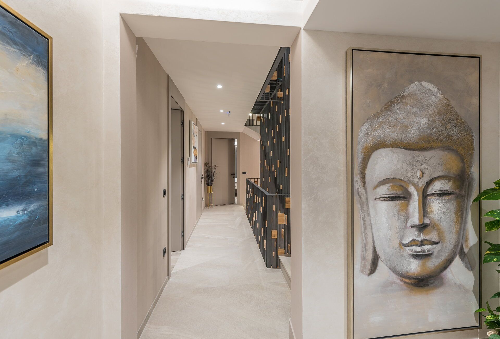 Un corridoio con una scala, un grande dipinto di Buddha e un design d'interni moderno.