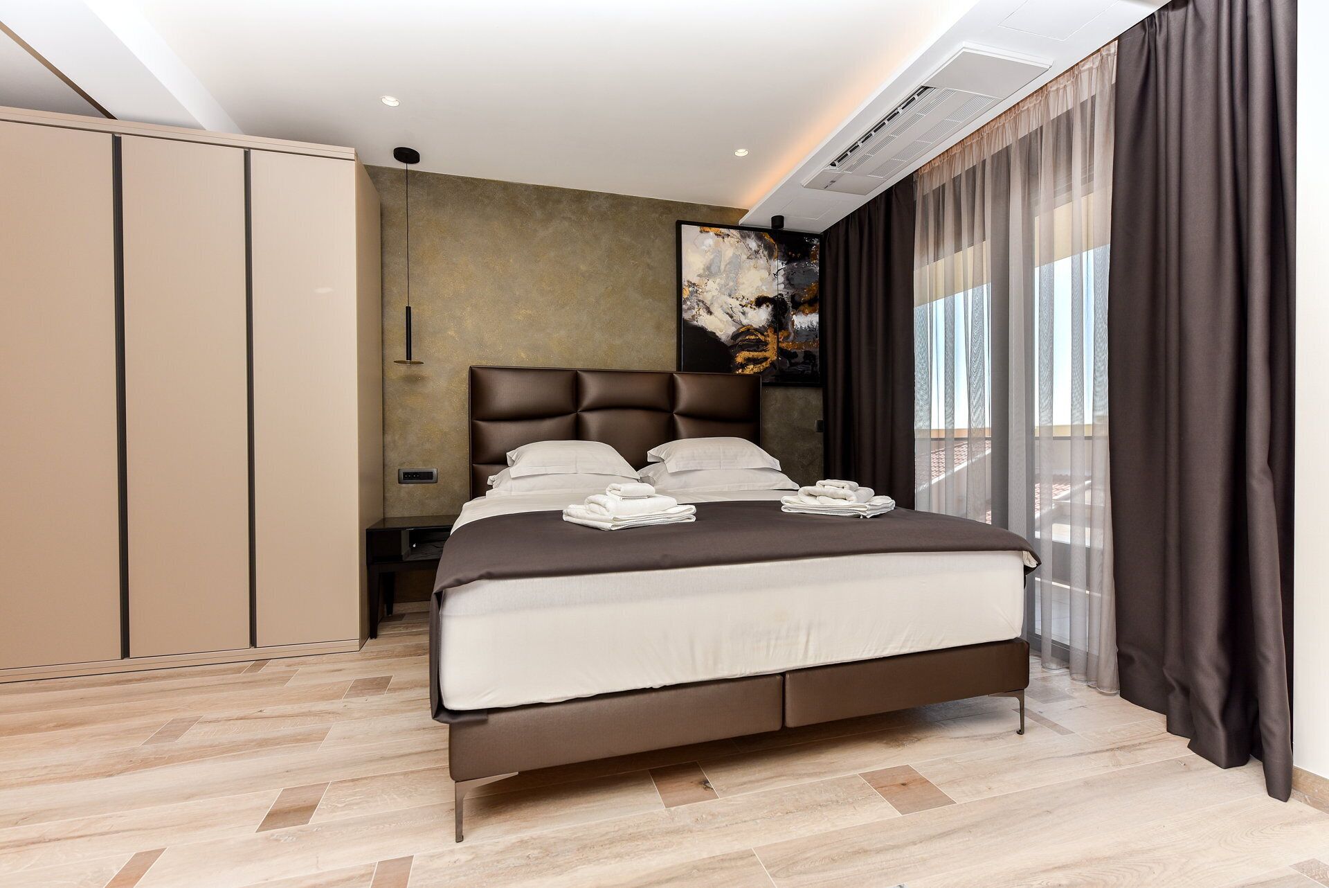 Ein modernes Schlafzimmer mit einem großen Bett, einem Kleiderschrank und einem Gemälde an der Wand.