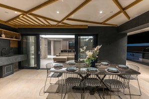 A modern dining area with a rectangular table set for six, surrounded by metal chairs with cushioned seats. - Luxury Villa Penelope with Pool (Makarska)