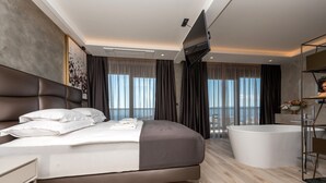 Una habitación de hotel moderna con una cama grande, una bañera y vistas a la ciudad.
