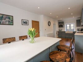 Una cocina moderna con gabinetes grises, una encimera blanca y una mesa de comedor de madera con cuatro sillas.