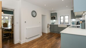 A modern kitchen with grey cabinets, a white countertop, and a built-in microwave. - Kylemore Railway Cottage (Stamford)