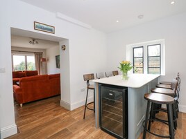 Una cocina moderna con una isla central, taburetes de bar y un área de comedor con un sofá rojo.