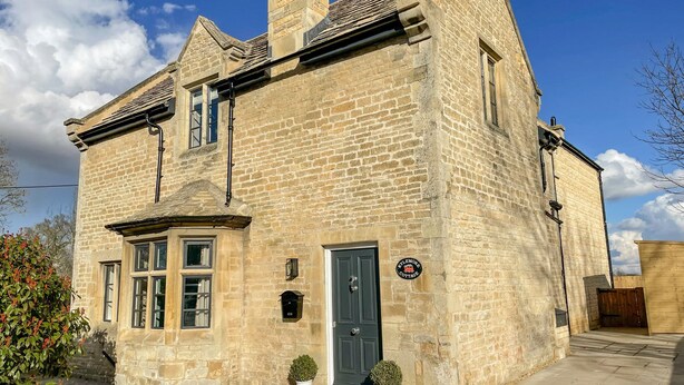 A stone building with a dark door, a small sign, and a potted plant in front. - Kylemore Railway Cottage (Stamford)