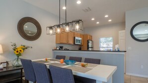 A modern kitchen with wooden cabinets, a stainless steel refrigerator, and a built-in oven. - Stylish 3BR 2.5BA Townhome Free Tub not overlooked (Kissimmee)