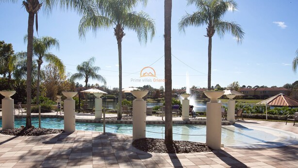 A pool area with palm trees, lounge chairs, and a clear sky. - Stylish 3BR 2.5BA Townhome Free Tub not overlooked (Kissimmee)