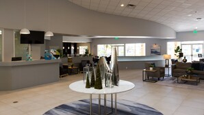 A spacious lobby with a reception desk, seating area, and large windows allowing natural light. - Stylish 3BR 2.5BA Townhome Free Tub not overlooked (Kissimmee)