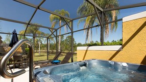 A hot tub with a glass enclosure, outdoor seating area, and palm trees in the background. - Stylish 3BR 2.5BA Townhome Free Tub not overlooked (Kissimmee)
