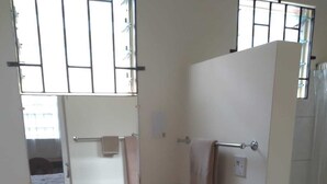 A bathroom with a white sink, mirror, and toilet. There are three drawers under the sink and a towel rack above the toilet. - The Grenada Escape (Saint George)
