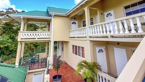 A multi-story building with balconies, a covered patio area, and potted plants. - The Grenada Escape (Saint George)