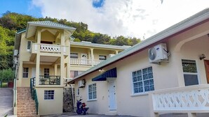 A two-story building with a balcony, a stone wall, and a parked motorcycle. - The Grenada Escape (Saint George)