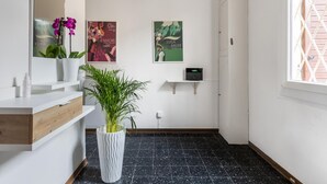 A bathroom with a white vanity, a potted plant, a mirror, and three posters on the wall. - Appartamento Alla Finestrella by Wonderful Italy (Bologna)