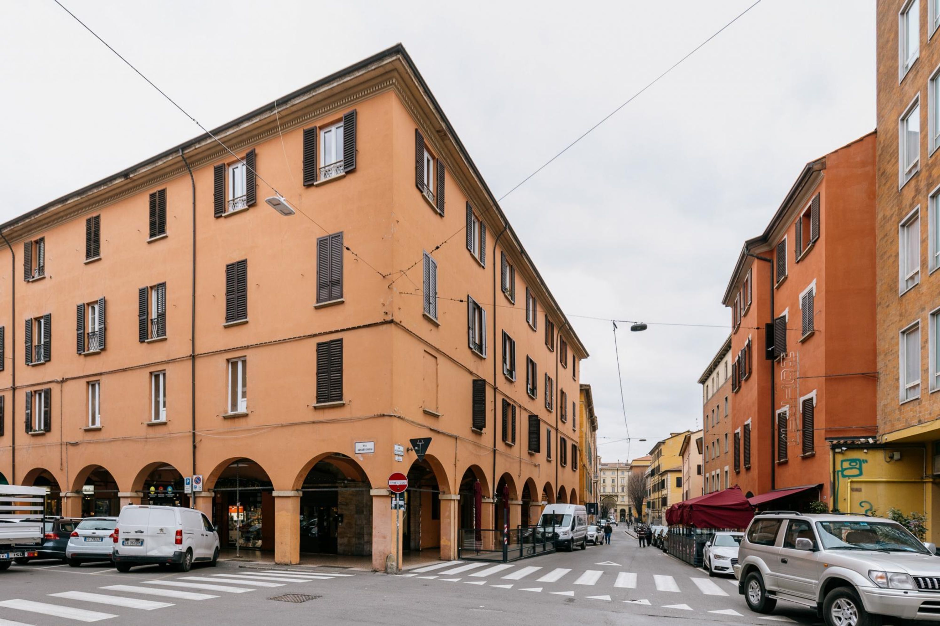 A street view with a building featuring arched doorways and a crosswalk.