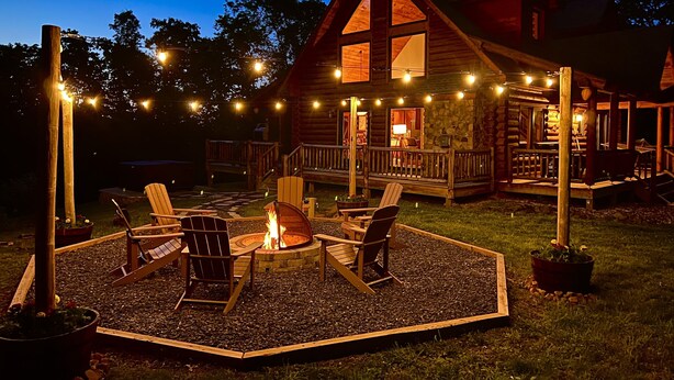 Une cabane en rondins dotée d’une terrasse, d’un espace salon extérieur et d’un foyer.