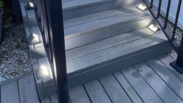 A wooden deck with a black railing, potted plants, and a white fence in the background. - Aviation Landing Vacation Homes Fallbrook CA (Fallbrook)
