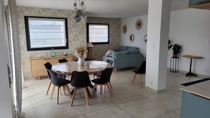 A dining area with a round table, chairs, a vase with dried flowers, and a wall-mounted light fixture. - 4-bedroom house in Terre d'Iroise (Lanildut)