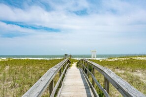 A wooden boardwalk leading to a lifeguard tower at the beach.