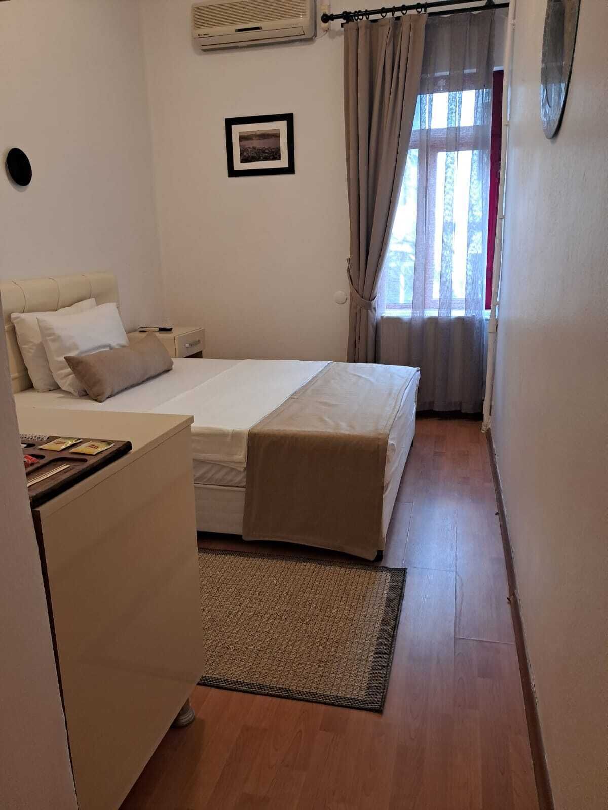 Une petite chambre à coucher, bien rangée, avec un lit, une table de chevet et un bureau.