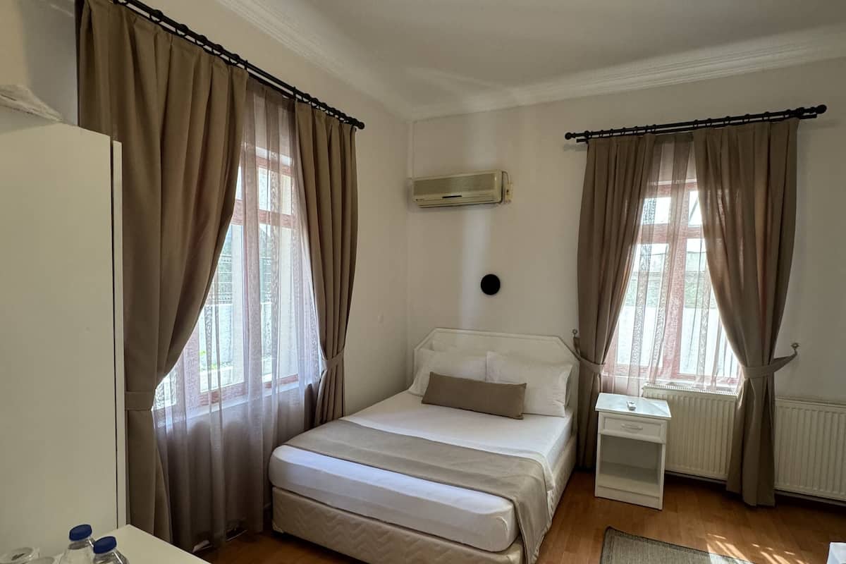 Une chambre à coucher avec un lit, une table de chevet, un radiateur et des rideaux.