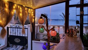 Zona de bar con vista al mar, decorada con guirnaldas de luces y faroles colgantes.