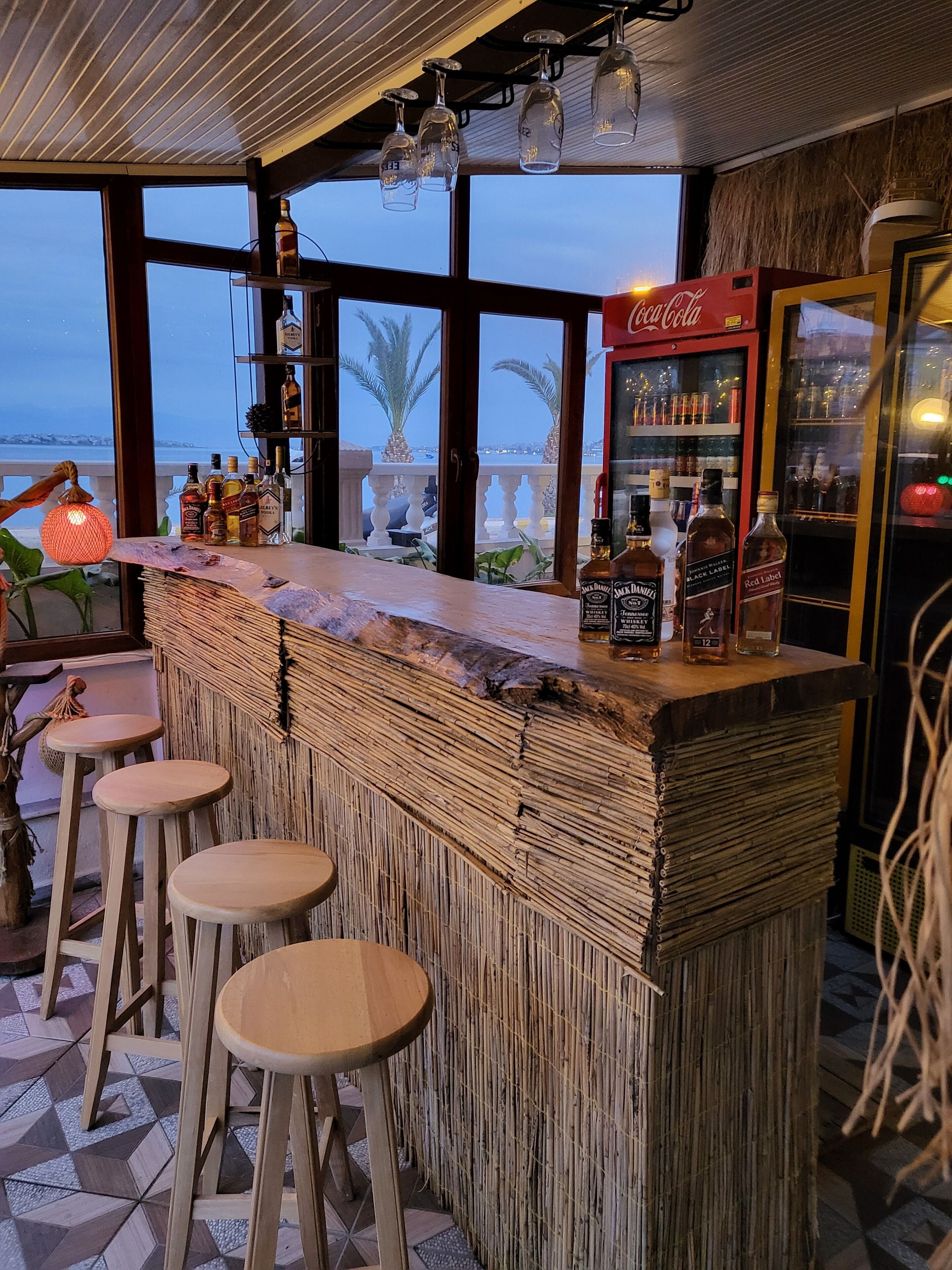 Angolo bar con bancone in legno, sgabelli e vista sul mare.