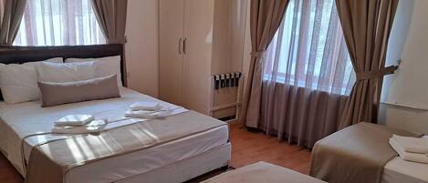 A hotel room with a bed, a sofa, a desk, and a wardrobe.