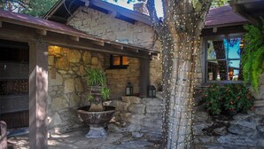 A stone building with a rustic stone fountain, lanterns, and string lights.