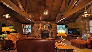 A cozy living room with a stone fireplace, leather sofas, and a television.