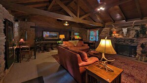 A cozy living room with a stone fireplace, leather sofa, and a television.