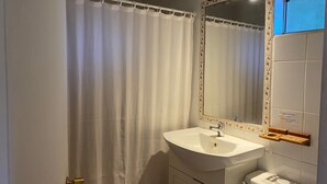 Un baño con un lavabo blanco, un espejo con marco decorativo y una cortina de ducha.