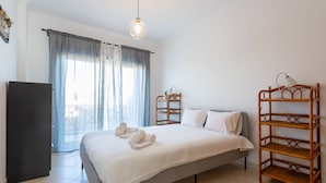 Un dormitori amb un llit, un armari, una tauleta de nit, una làmpada i una finestra amb cortines.