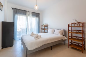 Une chambre à coucher avec un lit, une armoire, une table de chevet, une lampe et une fenêtre avec des rideaux.