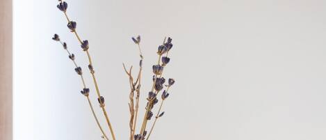 A clear glass vase with dried lavender stems tied with twine, placed on a wooden surface next to a glass cube containing small stones.