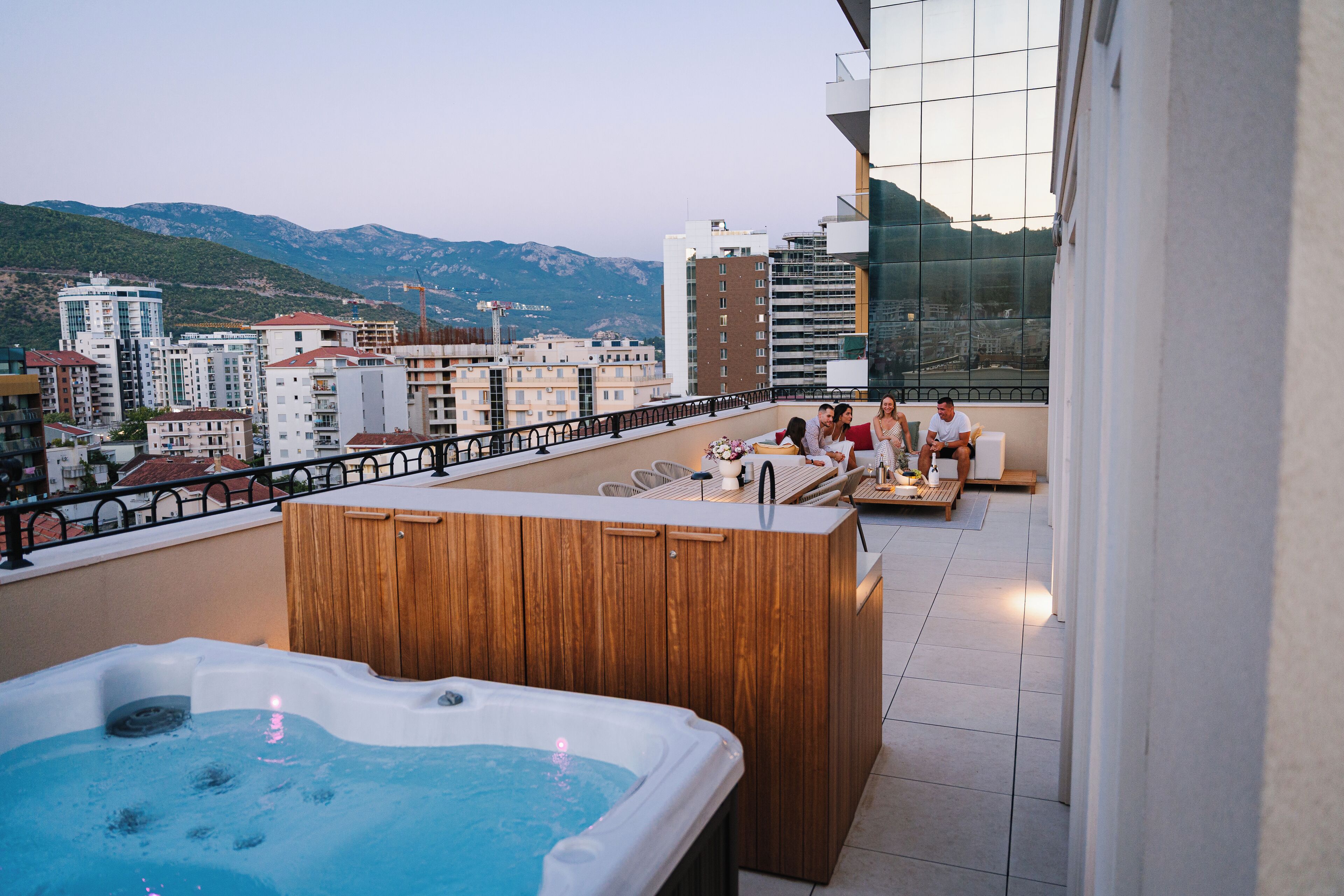 Una terraza en la azotea con jacuzzi, zona de estar y vistas a la ciudad y montañas.